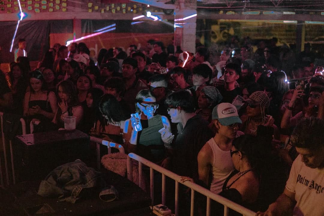 Multitude of young people dancing and drinking in a big warehouse space