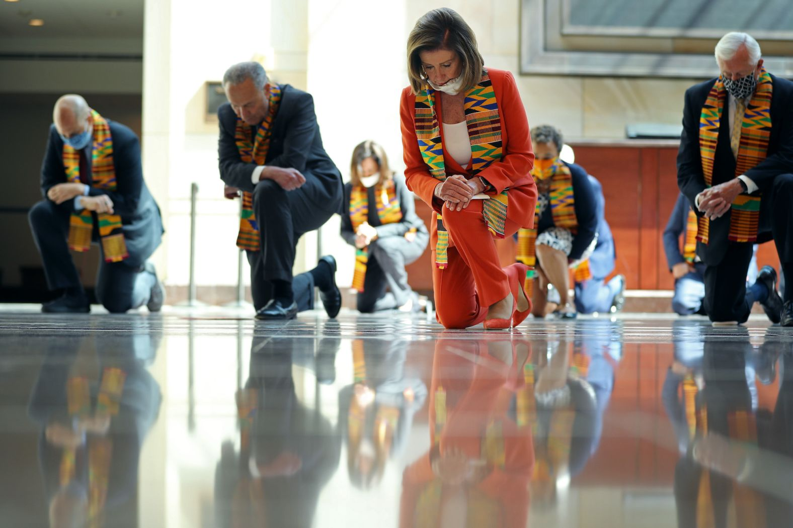 nancy pelosi and other politicians kneeling with kente cloths over their necks